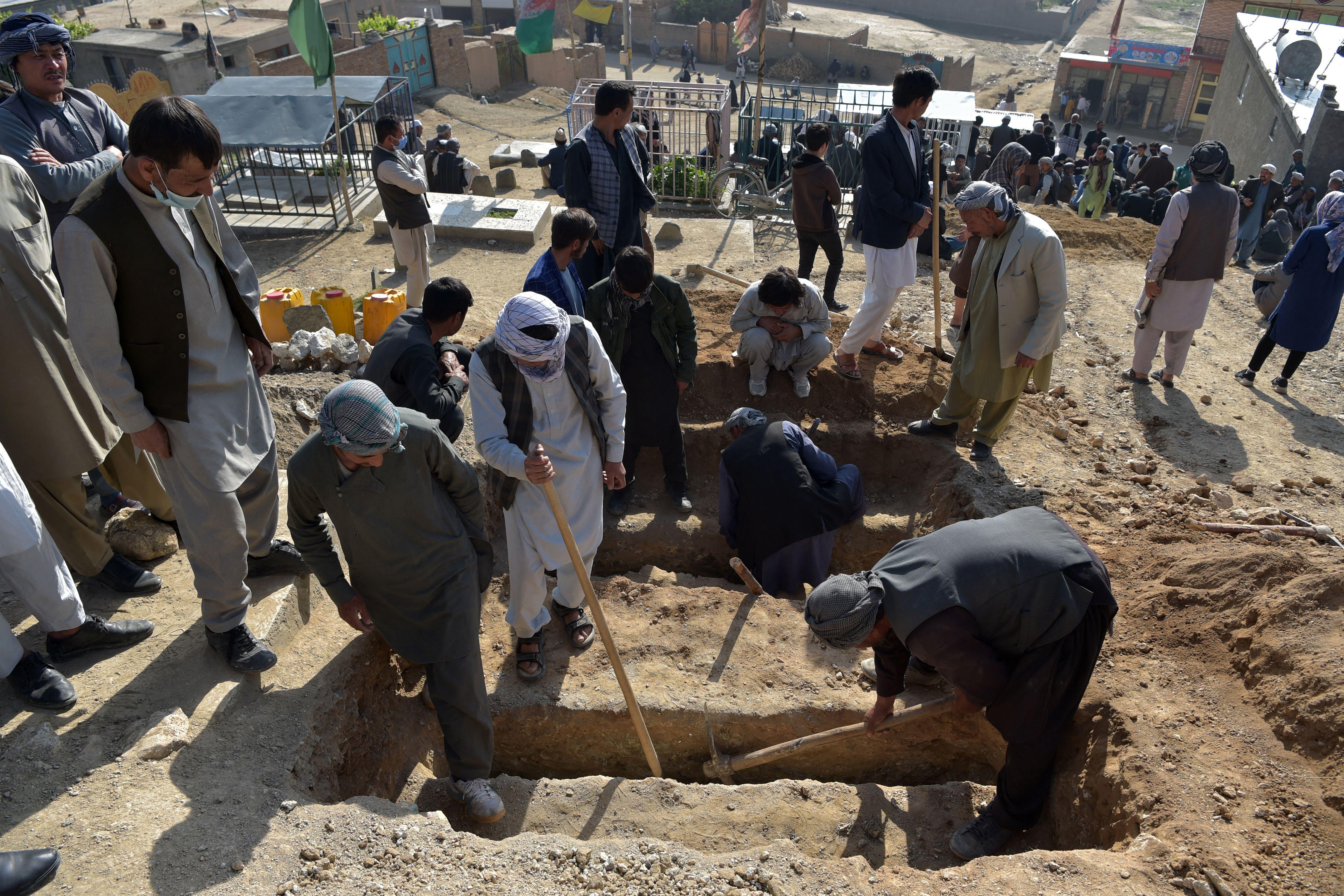 Shiite mourners and relatives dig graves for girls, who died in yesterday's multiple blasts outside a girls' school, during the burial at a desolate hilltop cemetery in Dasht-e-Barchi on the outskirts of Kabul on May 9, 2021.