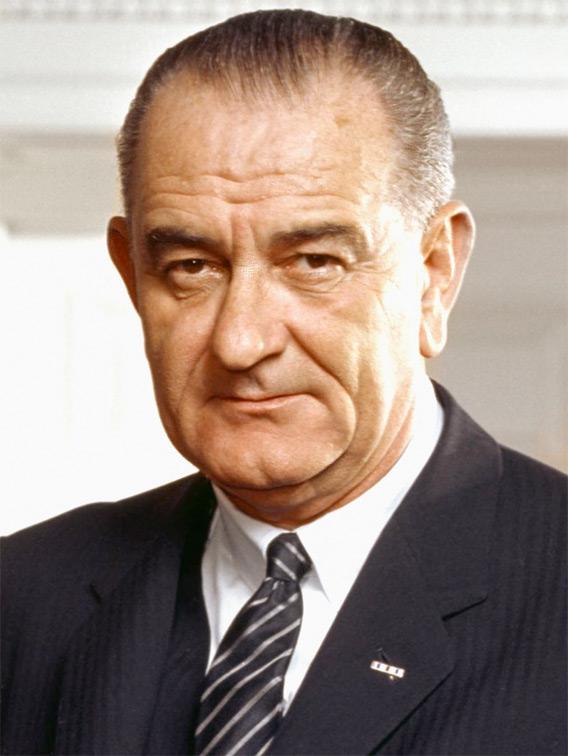 Photo portrait of President Lyndon B. Johnson in the Oval Office, leaning on a chair.