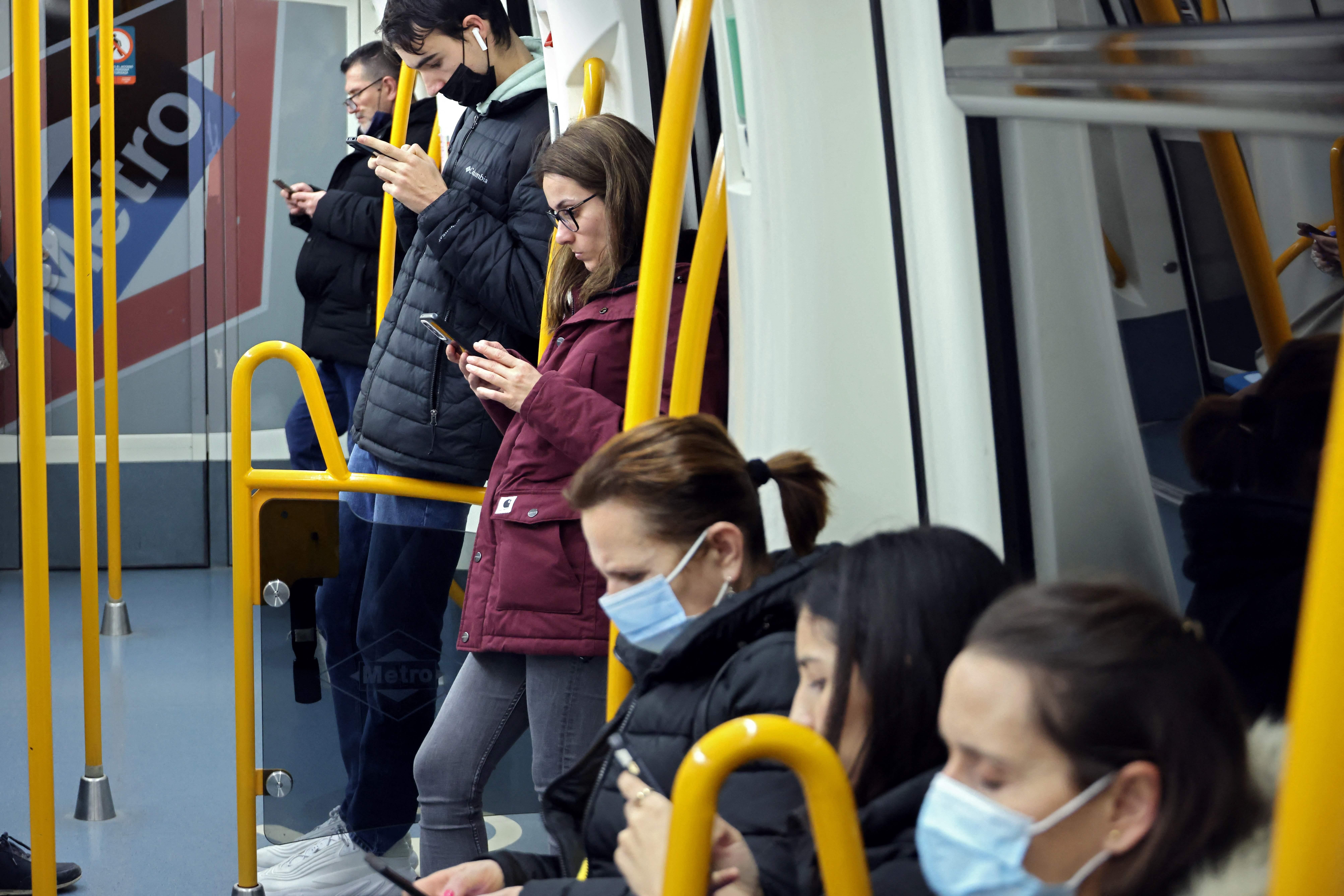 Passengers with and without face mask stand in the Madrids subway on February 7, 2023. They are mostly wearing blue medical masks.