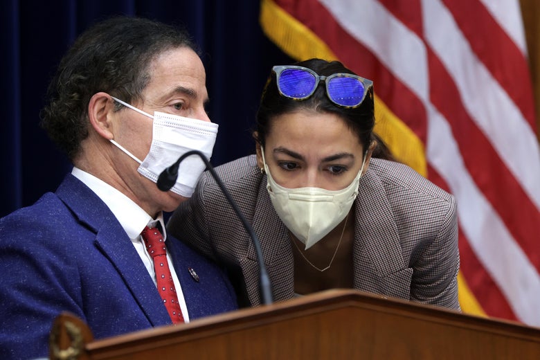 Masked Ocasio-Cortez leans over to listen to something masked Raskin says.