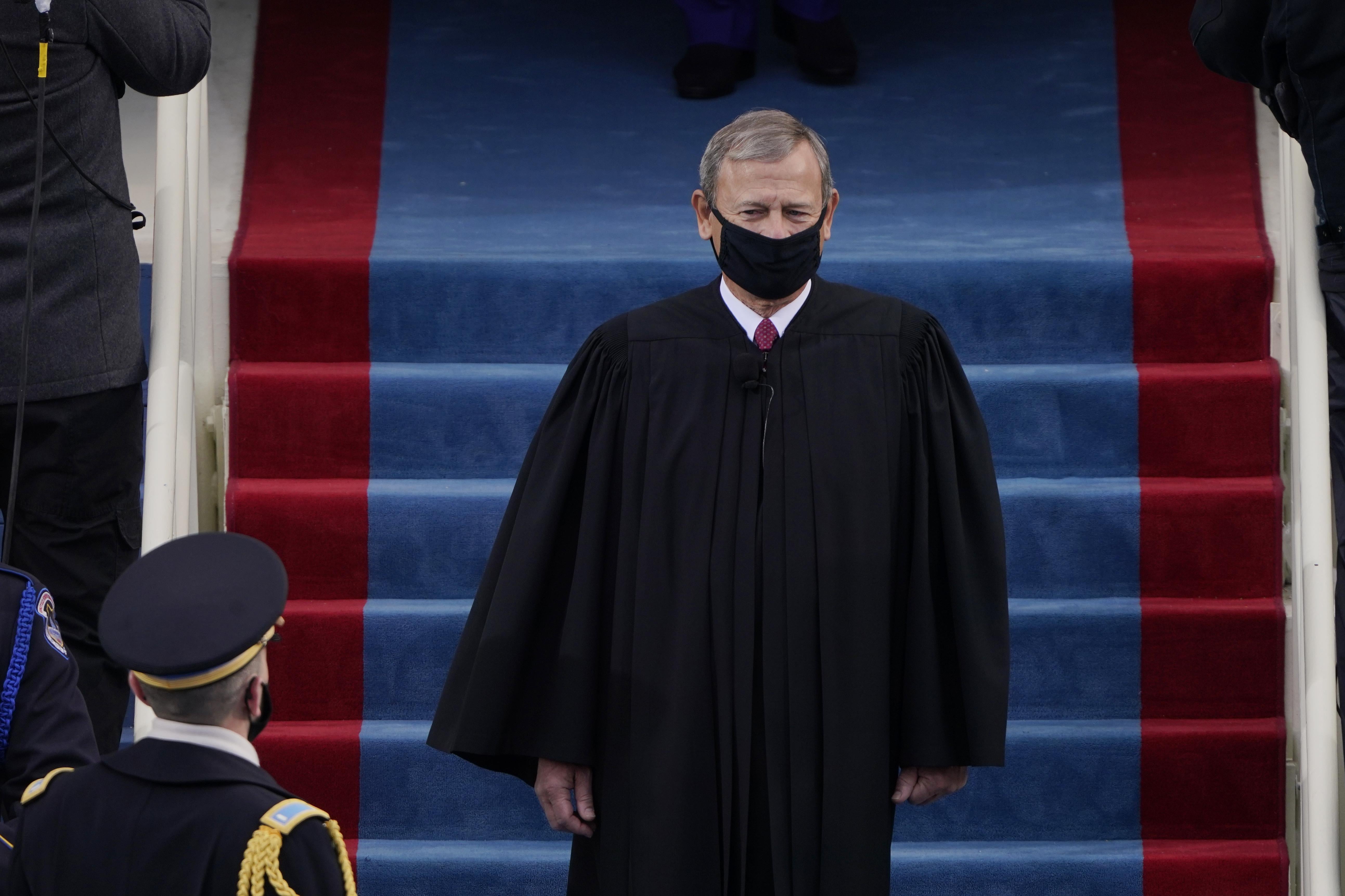 Chief Justice John Roberts wearing his judicial robe and a black mask.