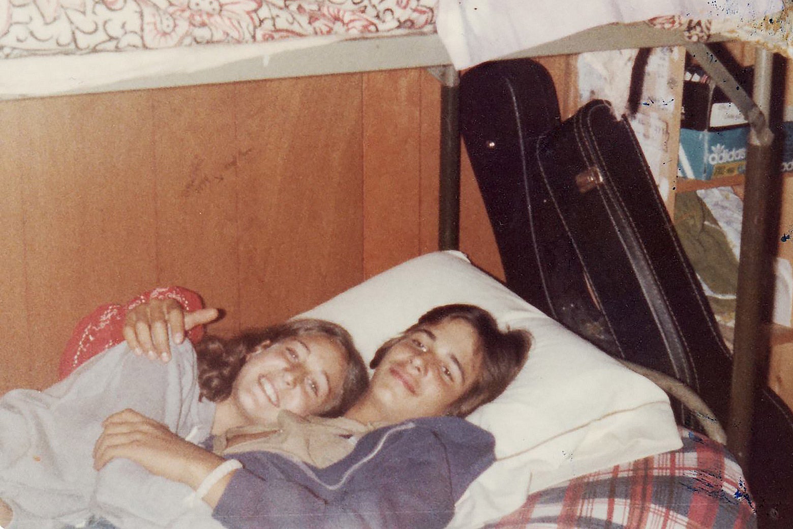 A couple lays together on the bottom bunk of a bunk bed.
