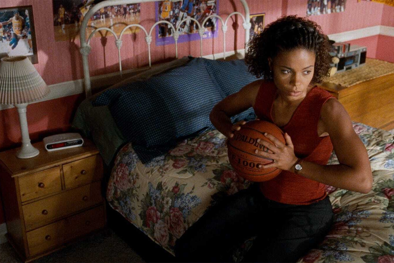 Woman in her bedroom holding a basketball.