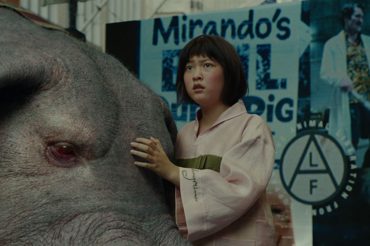 In a scene from Okja, Ahn Seo-hyun hugs her superpig protectively.