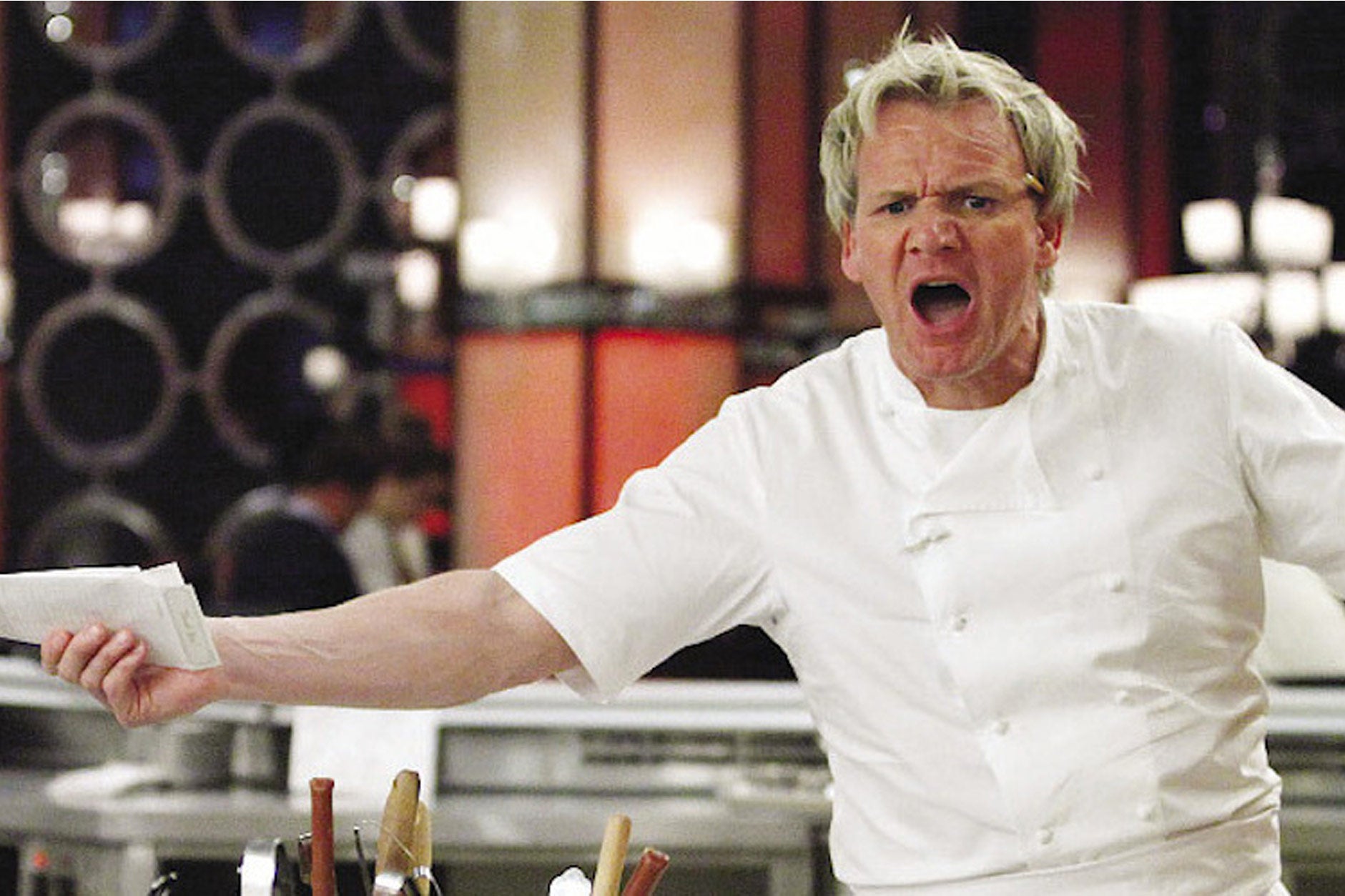 Gordon Ramsay yelling while holding restaurant tickets, in a still from one of his reality TV shows.