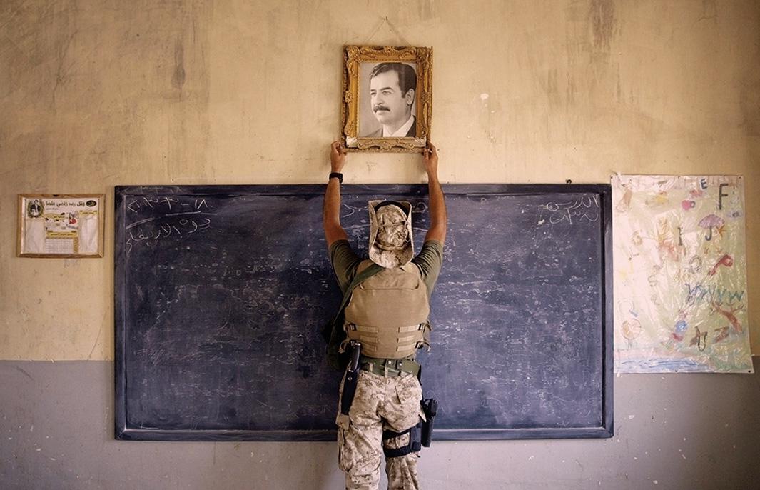 A Marine pulls down a picture of Saddam Hussein at a school on April 16, 2003, in Al-Kut, Iraq. U.S. troops went to schools and other facilities looking for weapons caches and unexploded bombs in preparation for removing and neutralizing them.