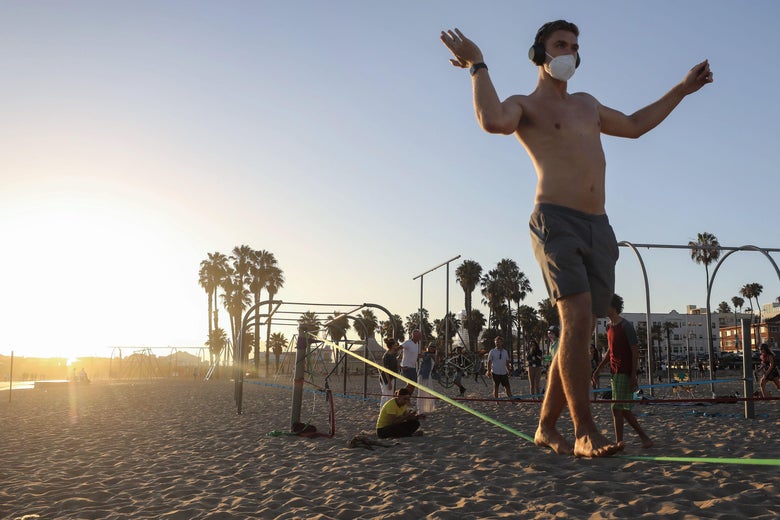 A man slacklines while wearing a face mask on Santa Monica beach amid the COVID-19 pandemic on July 2, 2020 in Santa Monica, California. Beginning July 3, Los Angeles County beaches and piers will be closed through the July 4th holiday weekend amid some reinstated restrictions intended to slow the spread of the coronavirus.