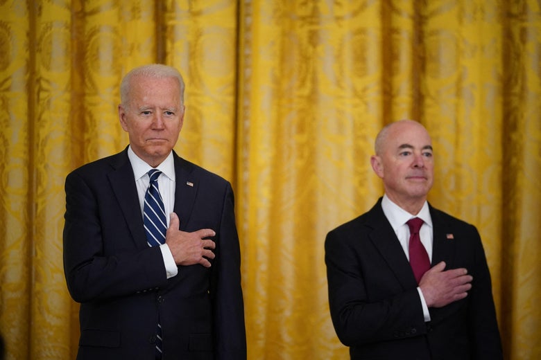 Biden and Mayorkas stand and hold their hands to their hearts