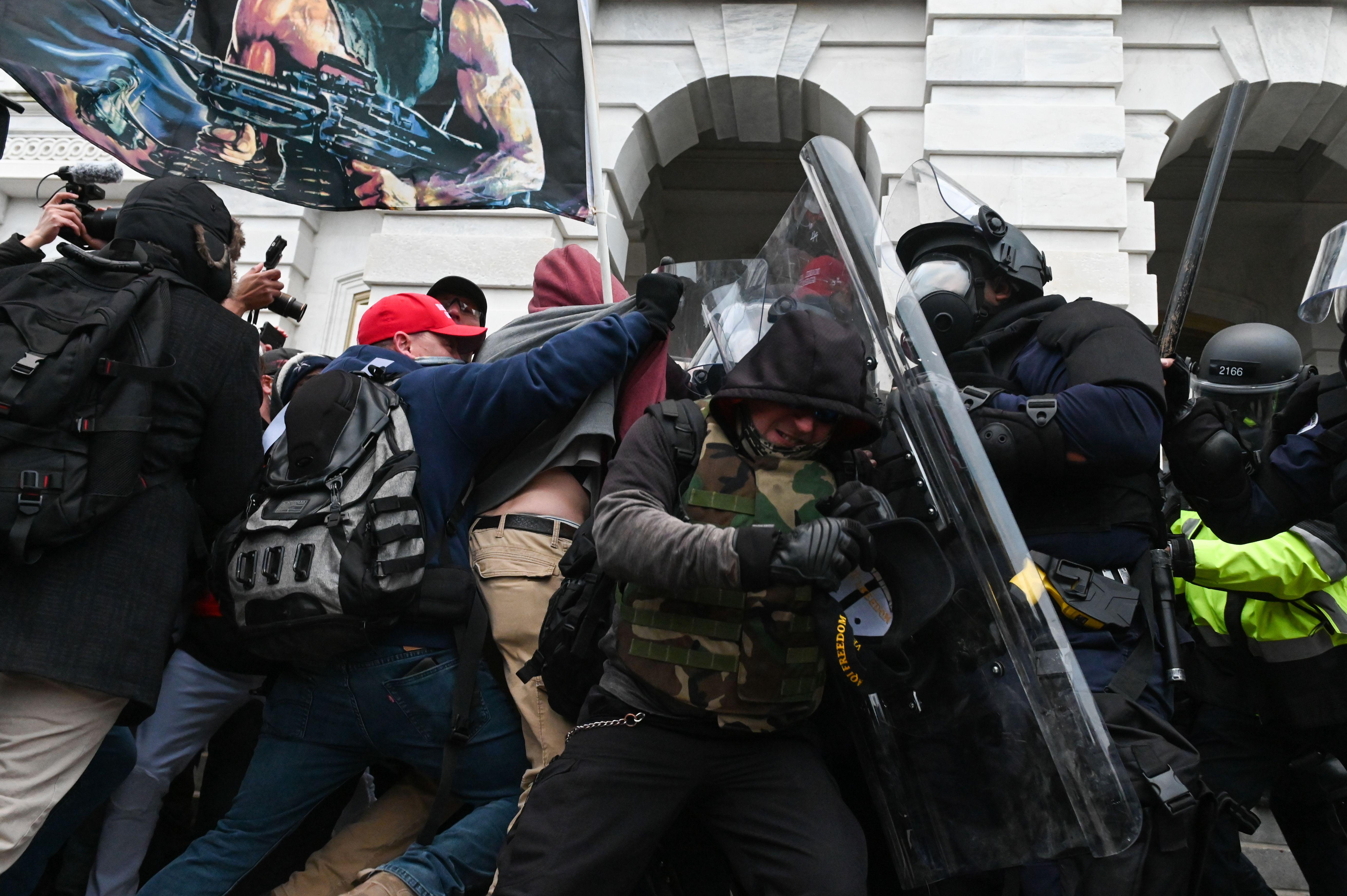 Pro-Trump rioters clash with police in riot gear.