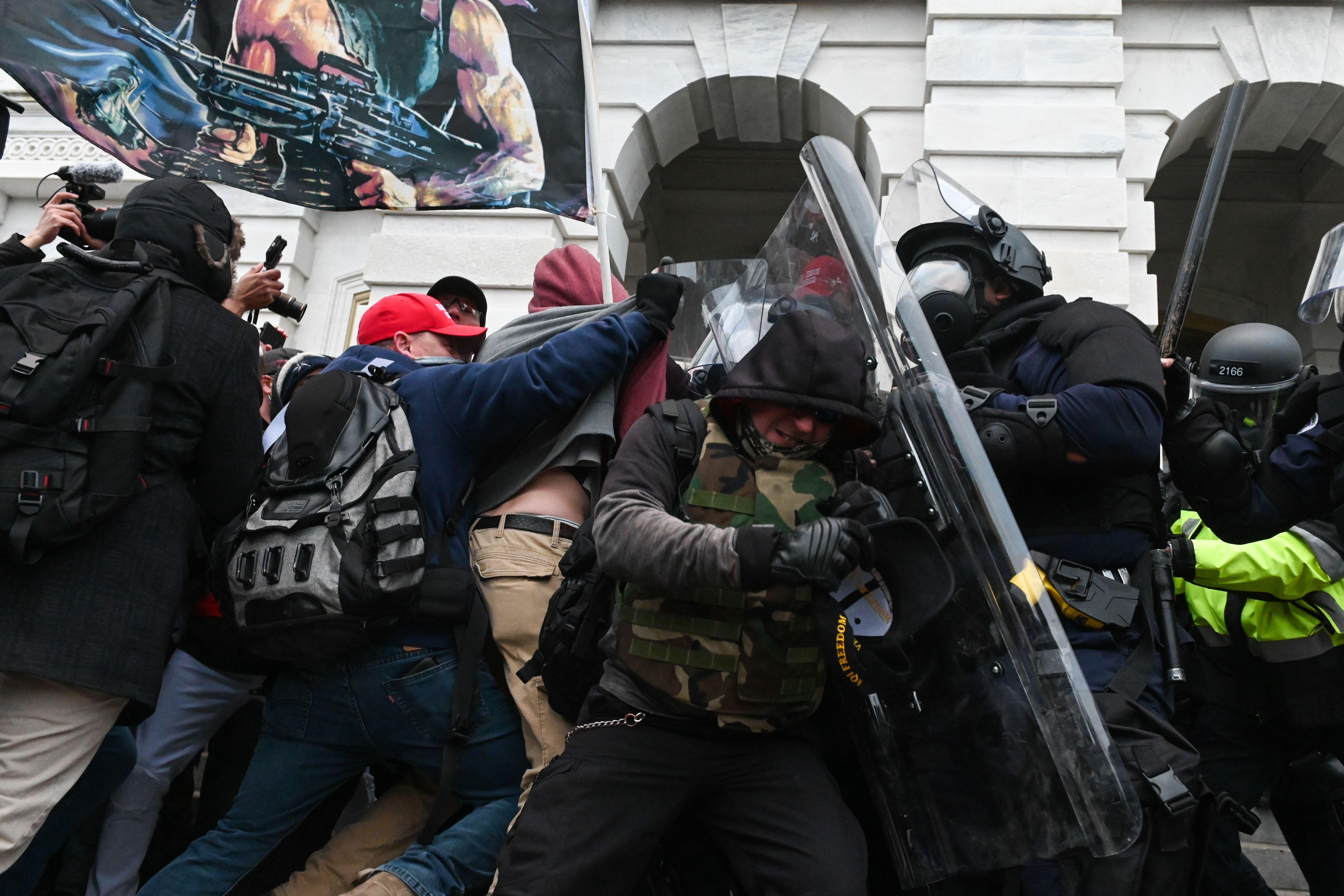 Pro-Trump rioters clash with police in riot gear.