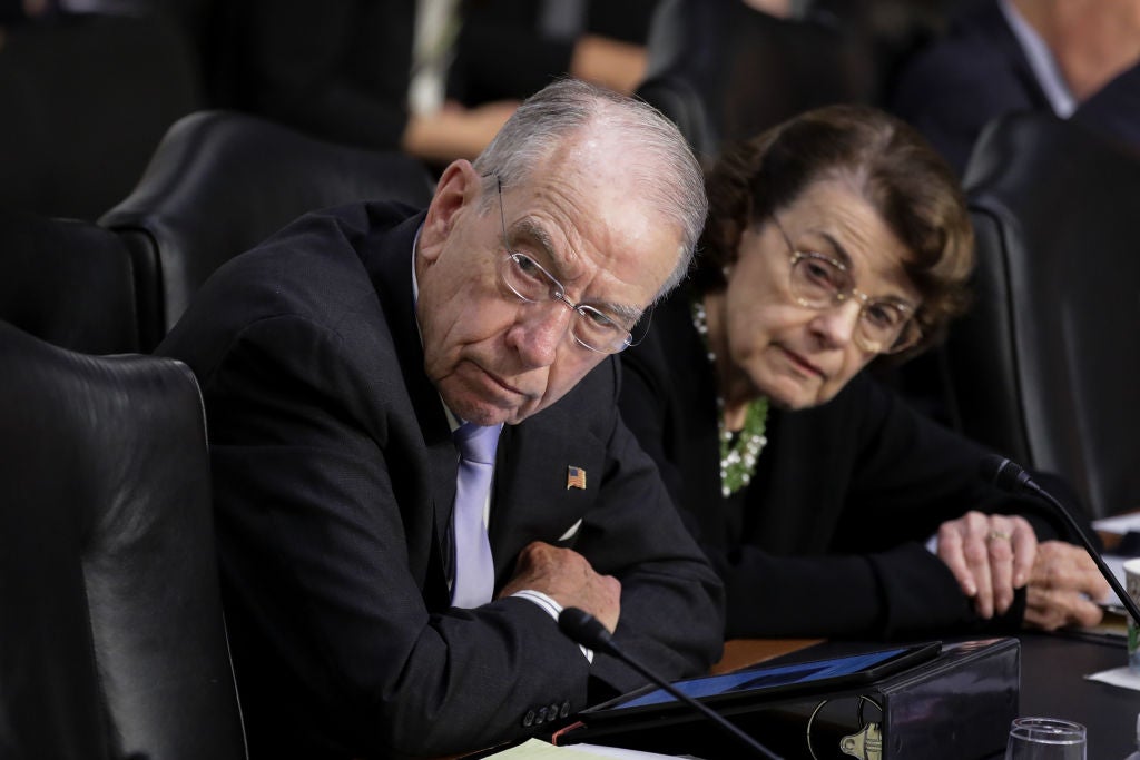 Grassley and Feinstein look to their right while seated at a committee hearing.