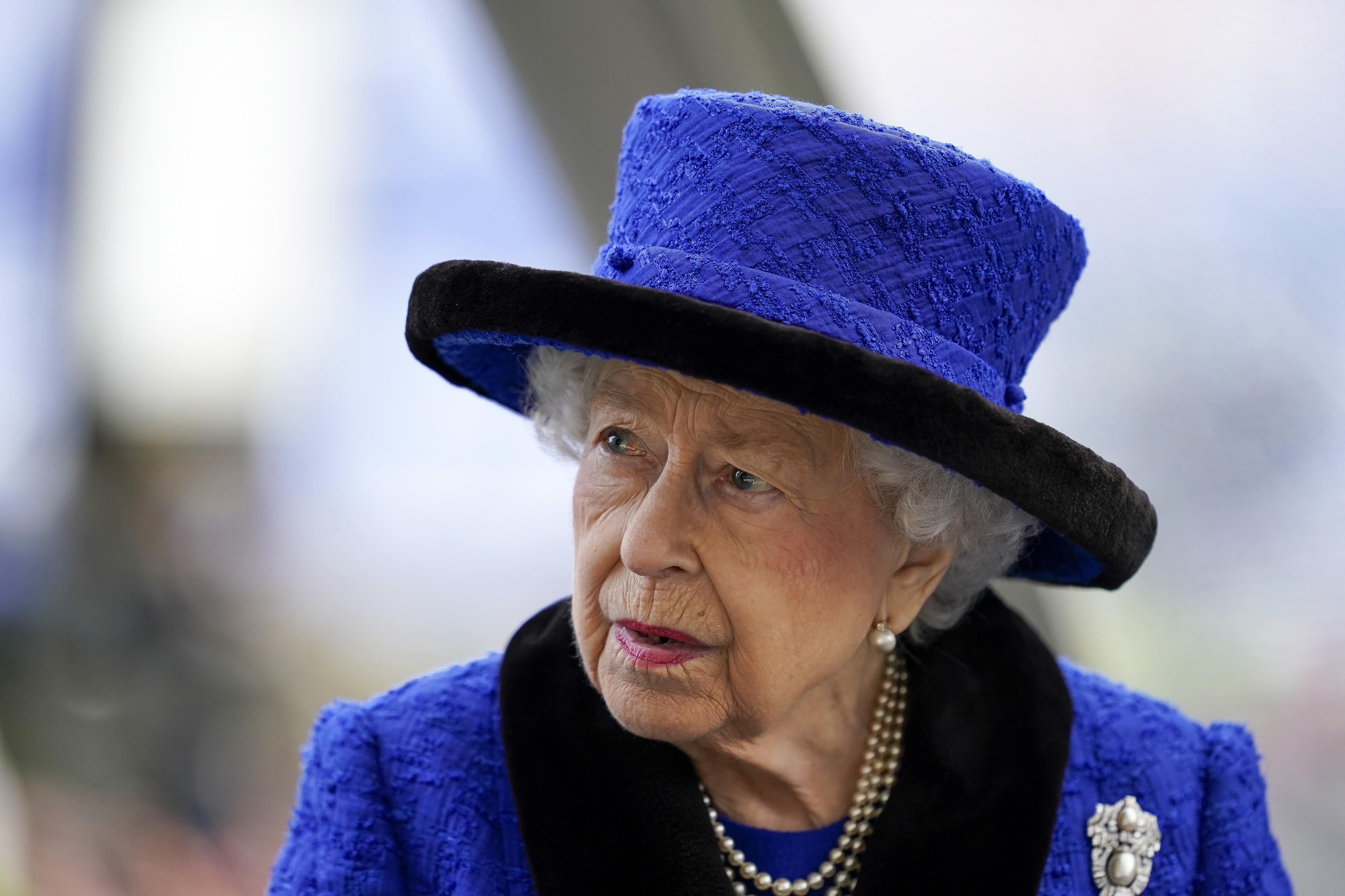 Queen Elizabeth II wears a blue brimmed hat and matching coat.