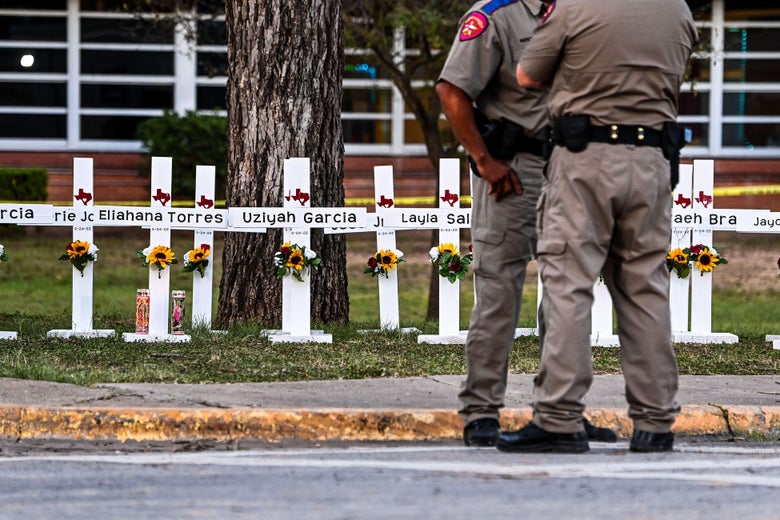 Police officers stand near a makeshift memorial for the shooting victims at Robb Elementary School