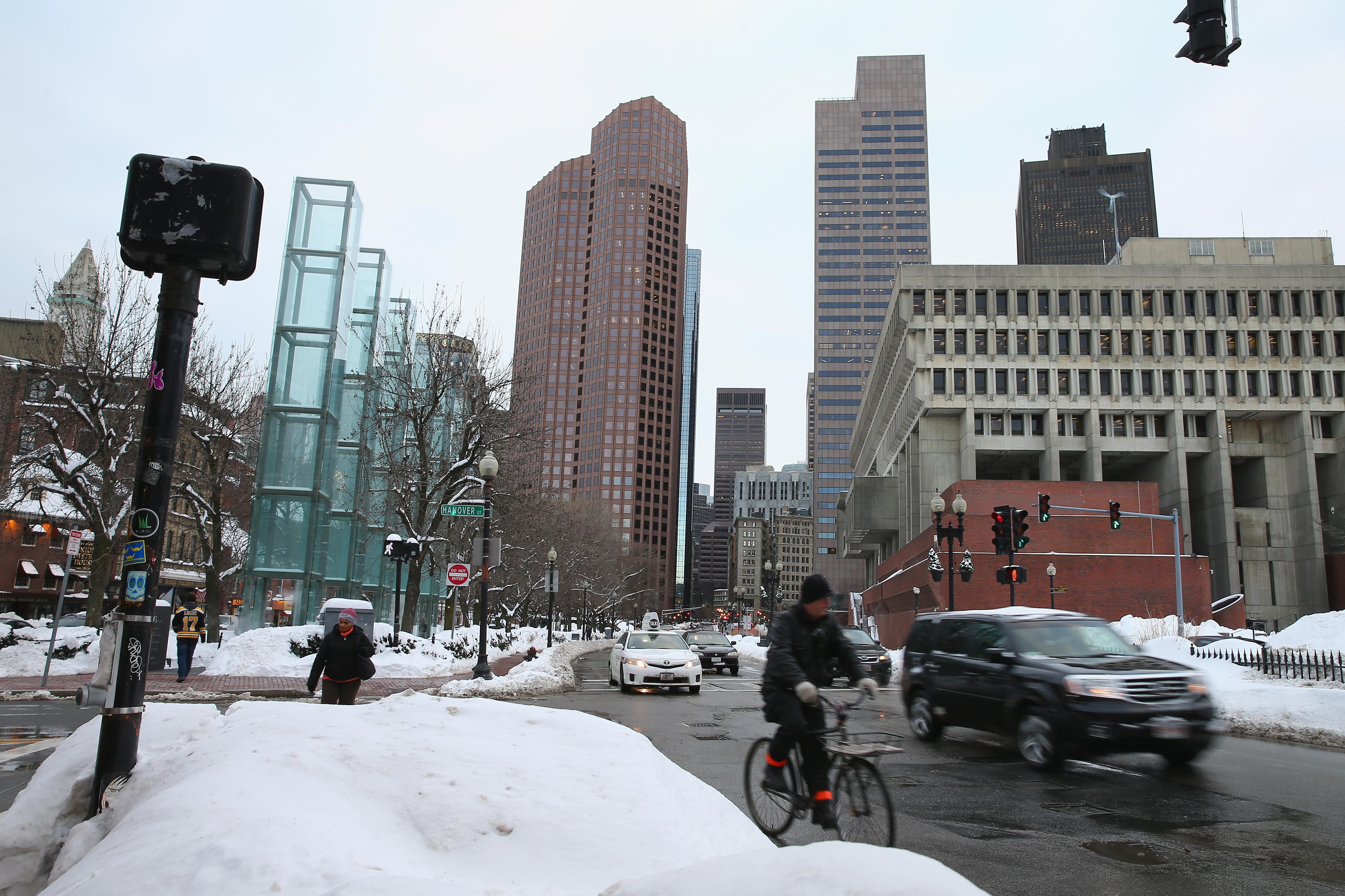 Cars and a biker at a snowy intersection in Boston.