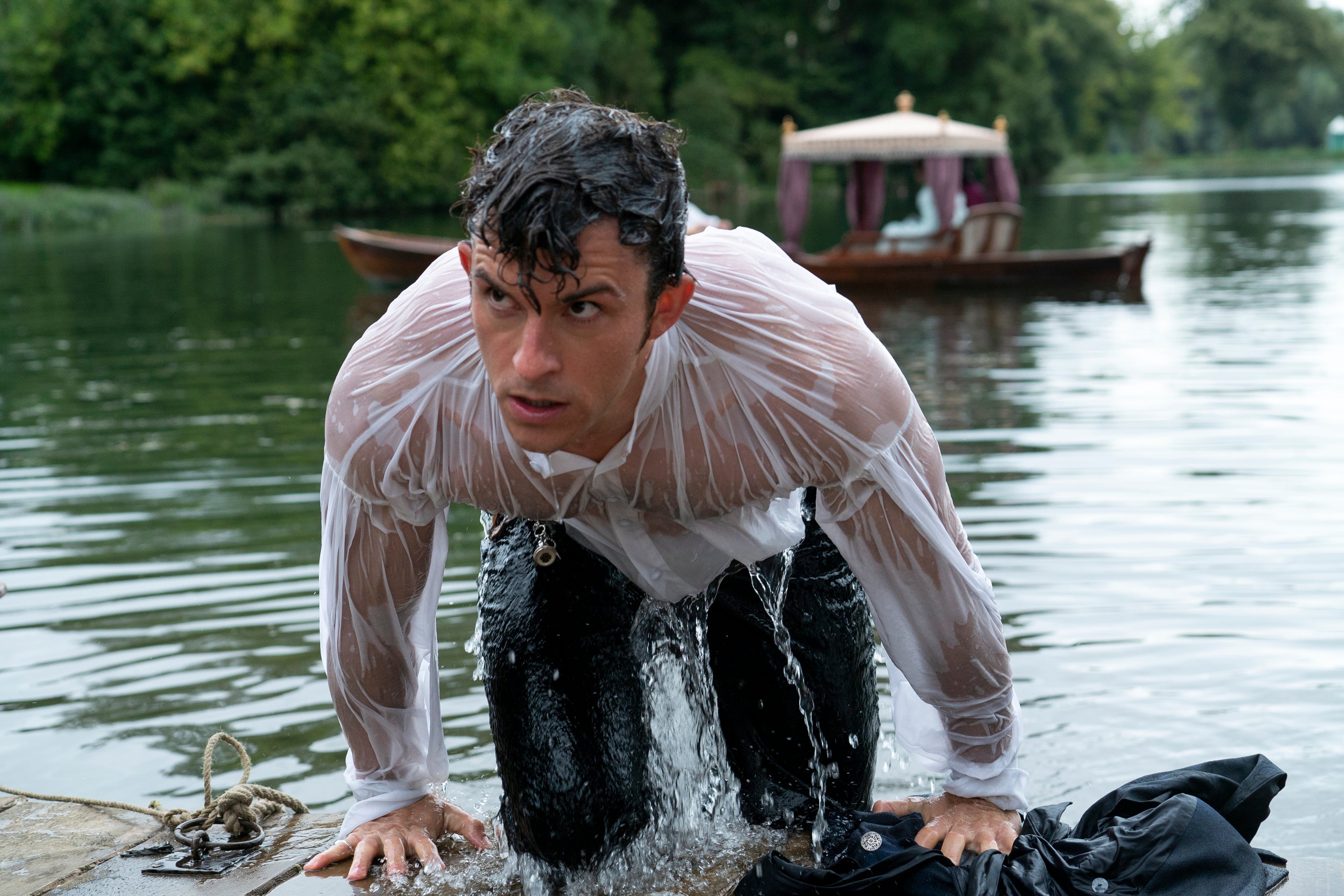 Jonathan Bailey emerges from a lake, his soaked hair and clothes plastered to his body.