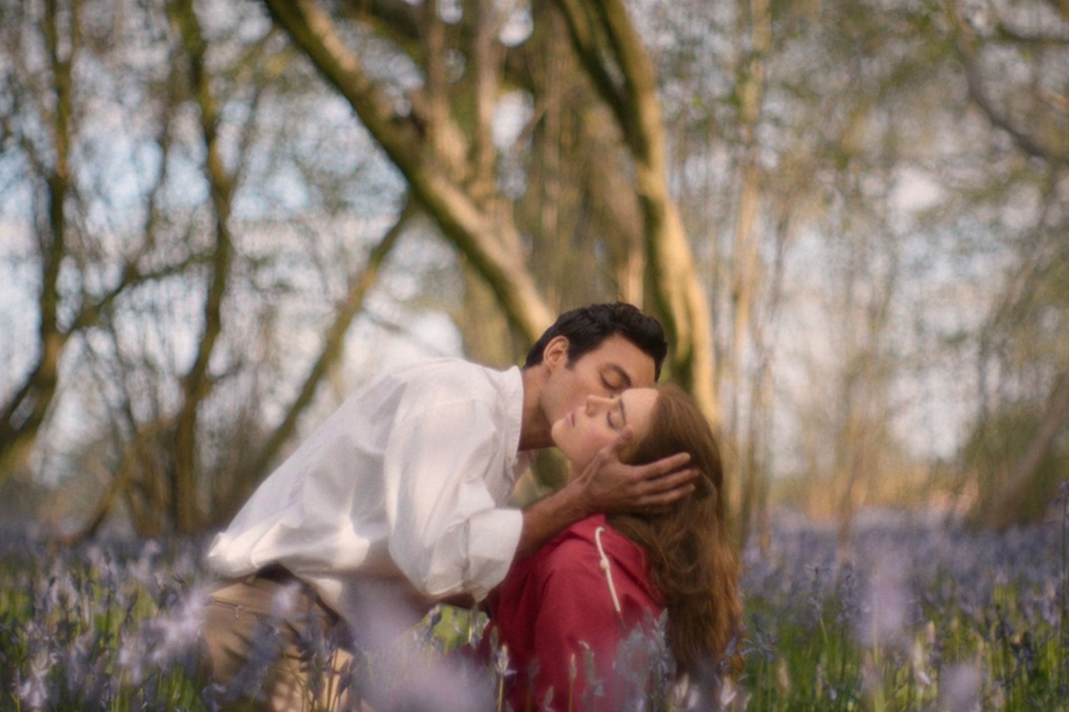 Taggie and Rupert kissing in a flower field.