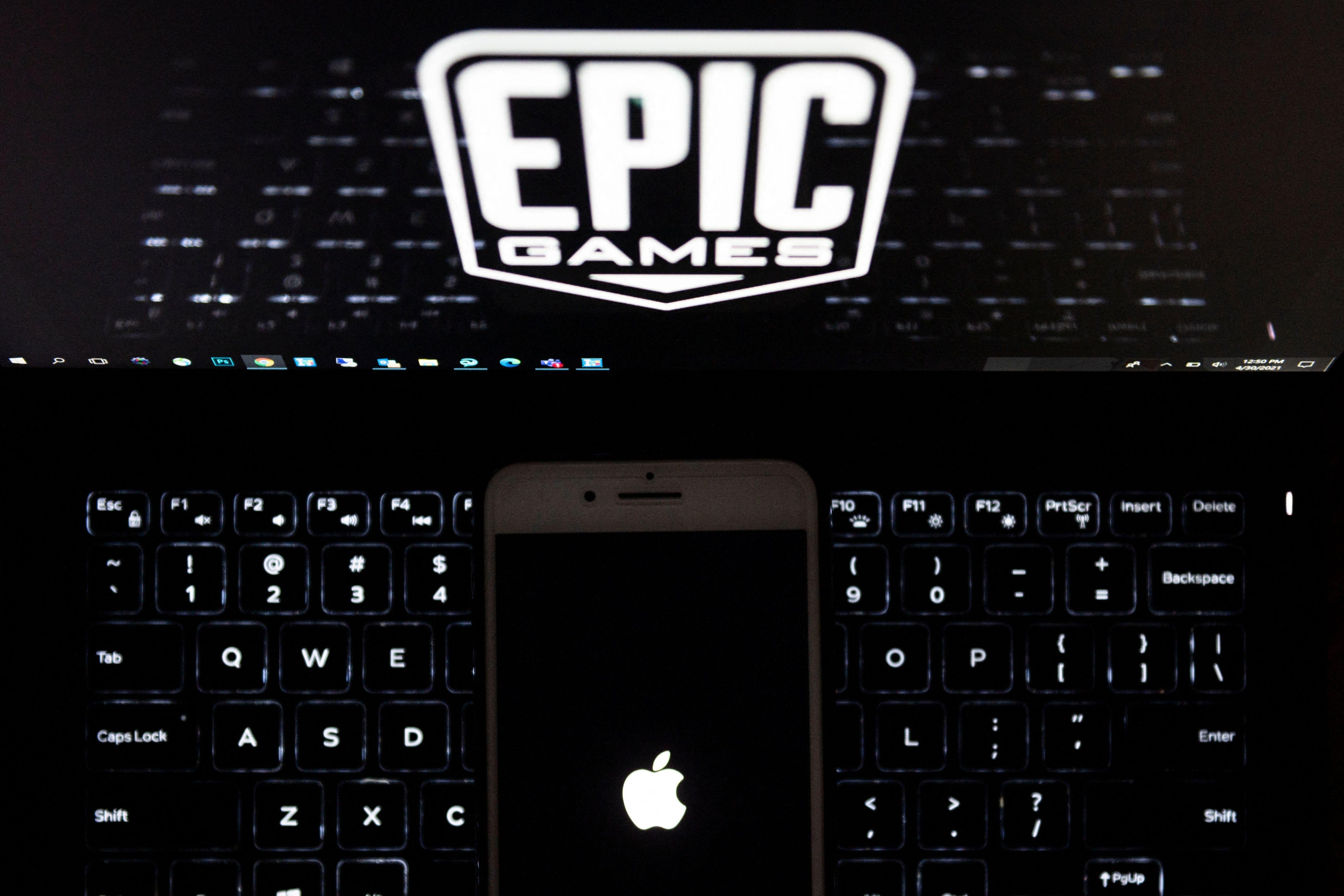 This illustration picture shows the logo from Epic Games displayed on a laptop and an Apple Logo on an iPhone in Arlington, Virginia on April 30, 2021. - In a court clash with potentially huge repercussions for the world of mobile tech, Fortnite maker Epic Games takes on Apple starting on May 3, 2021, aiming to break the grip of the iPhone maker on its online marketplace. - RESTRICTED TO EDITORIAL USE (Photo by Andrew CABALLERO-REYNOLDS / AFP) / RESTRICTED TO EDITORIAL USE (Photo by ANDREW CABALLERO-REYNOLDS/AFP via Getty Images)