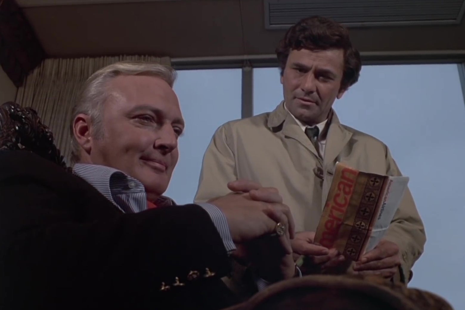 Jack Cassidy and Peter Falk in a still from the Columbo episode "Murder by the Book." Cassidy sits in the foreground, smirking; Columbo stands behind him asking a question.