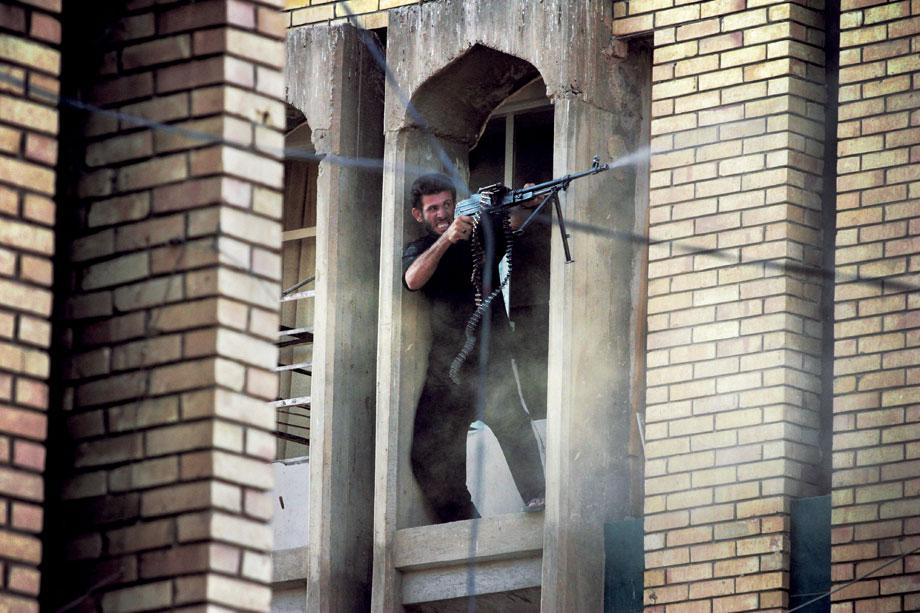 NAJAF, Iraq—A militiaman loyal to Shi’ite cleric Muqtada al-Sadr fires toward U.S. positions on the western border of Najaf’s old city. Militiamen engaged U.S. forces with mortars, rocket-propelled grenades, and small arms fire, Aug. 22, 2004.