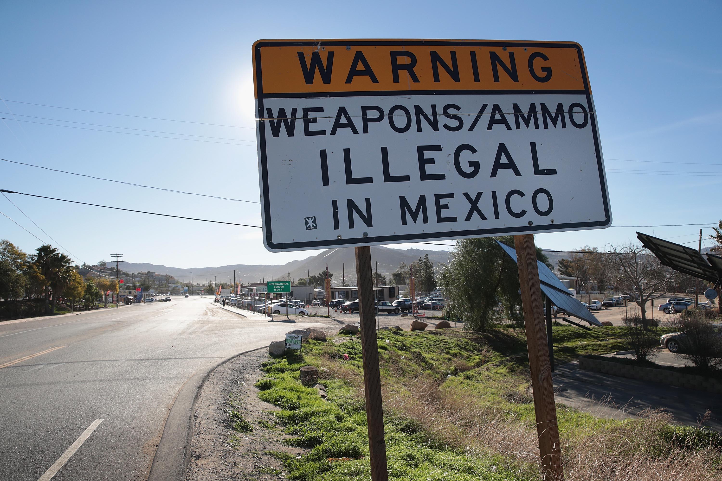 A sign along a road reads, "WARNING: WEAPONS/AMMO ILLEGAL IN MEXICO."