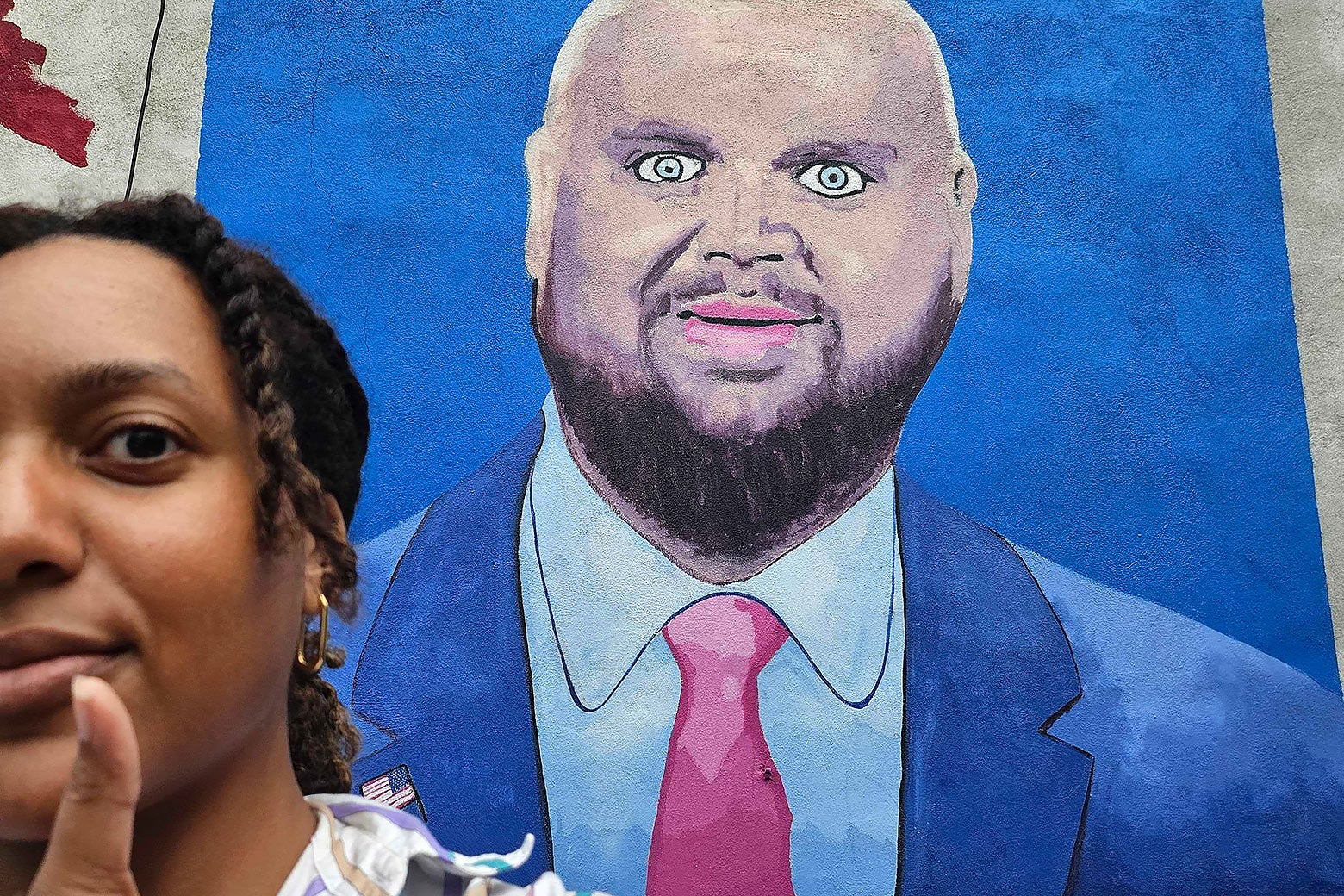 Nadira Goffe taking a selfie, with a thumbs up, in front of the J.D. Vance mural.