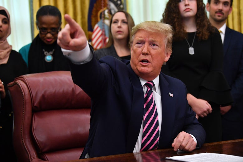 Donald Trump sitting at a desk pointing