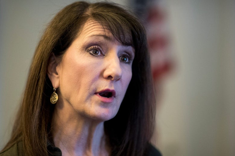 A white woman with brown hair cocks her head to the side as she speaks.
