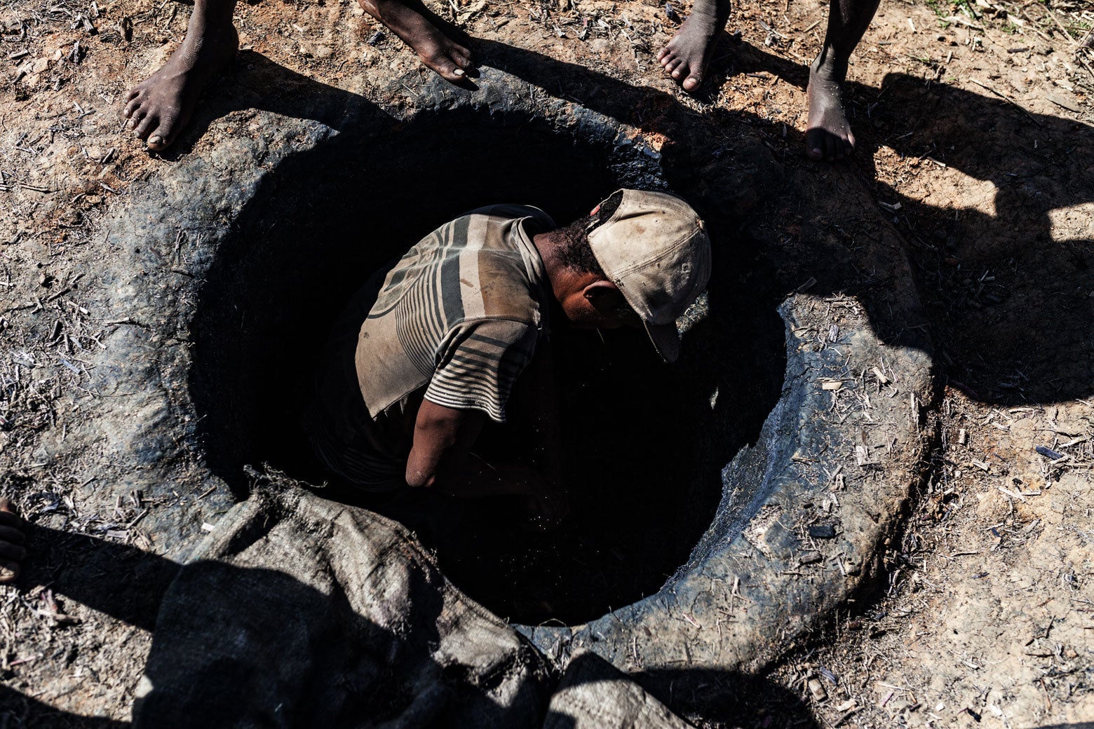 Fermented sugarcane pulp is excavated from a fired pit in the clay soil.
