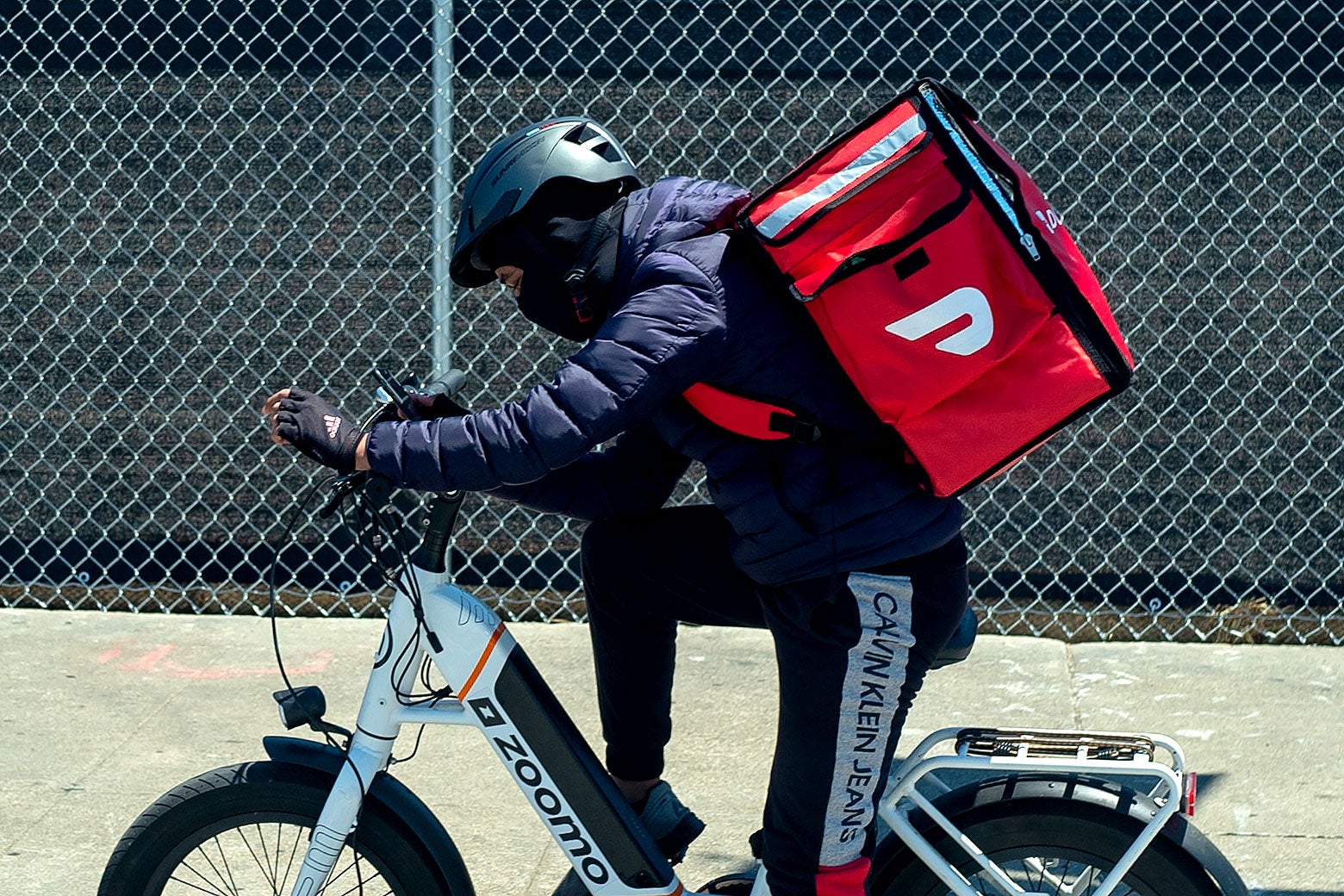 A DoorDash delivery person on a bike with a large delivery bag on their back.