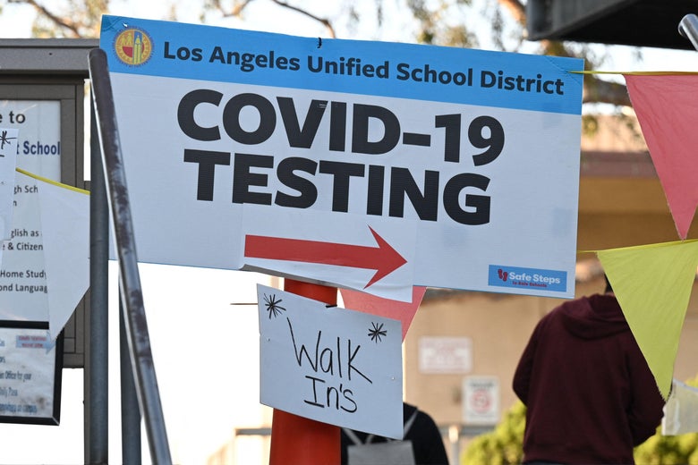A sign from the Los Angeles Unified School District reads "COVID-19 Testing" with an arrow. A note pasted below reads "Walk Ins."