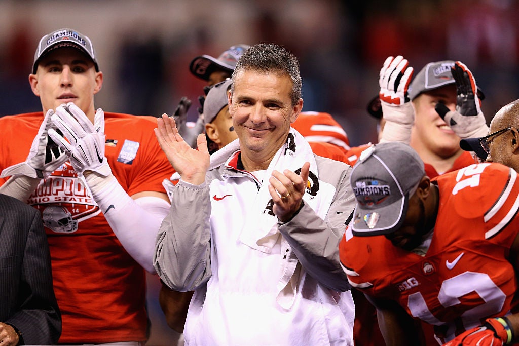 Meyer, surrounded by players, claps with a smug expression on his face.