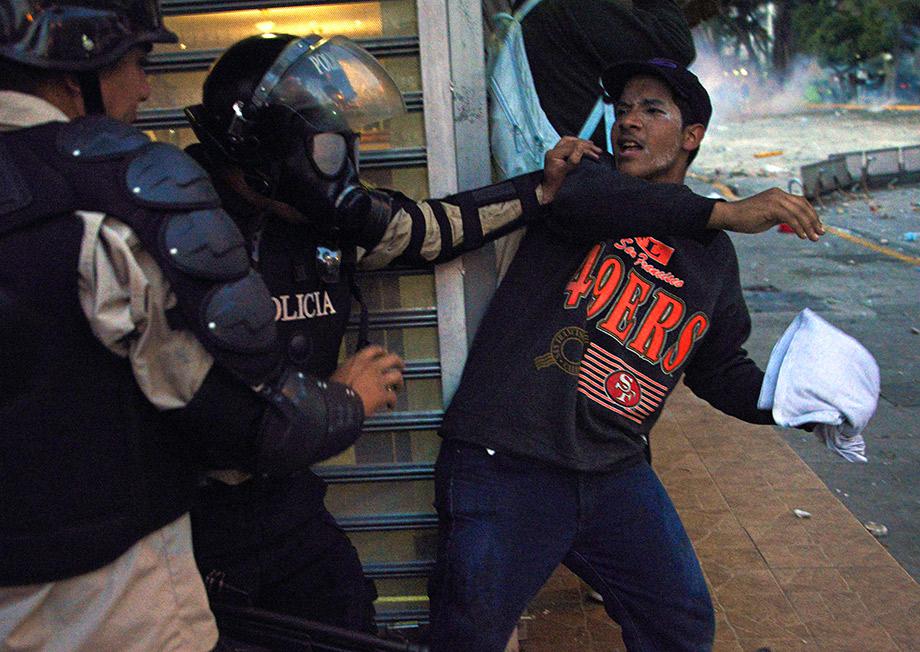 A member of the National Police struggles with an anti-government student taking part in a protest, in Caracas.