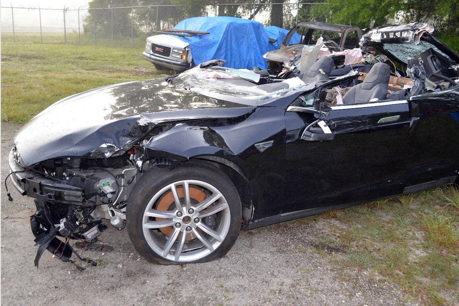 A mangled Tesla Model S on a patch of grass.