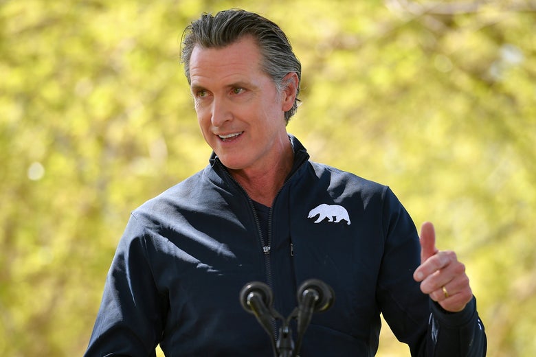 Gavin Newsom speaks outside while standing at a micorphone.