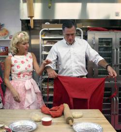 Mitt Romney puts on a apron as Linda Hundt, owner of Sweetie-licious Bakery Café.