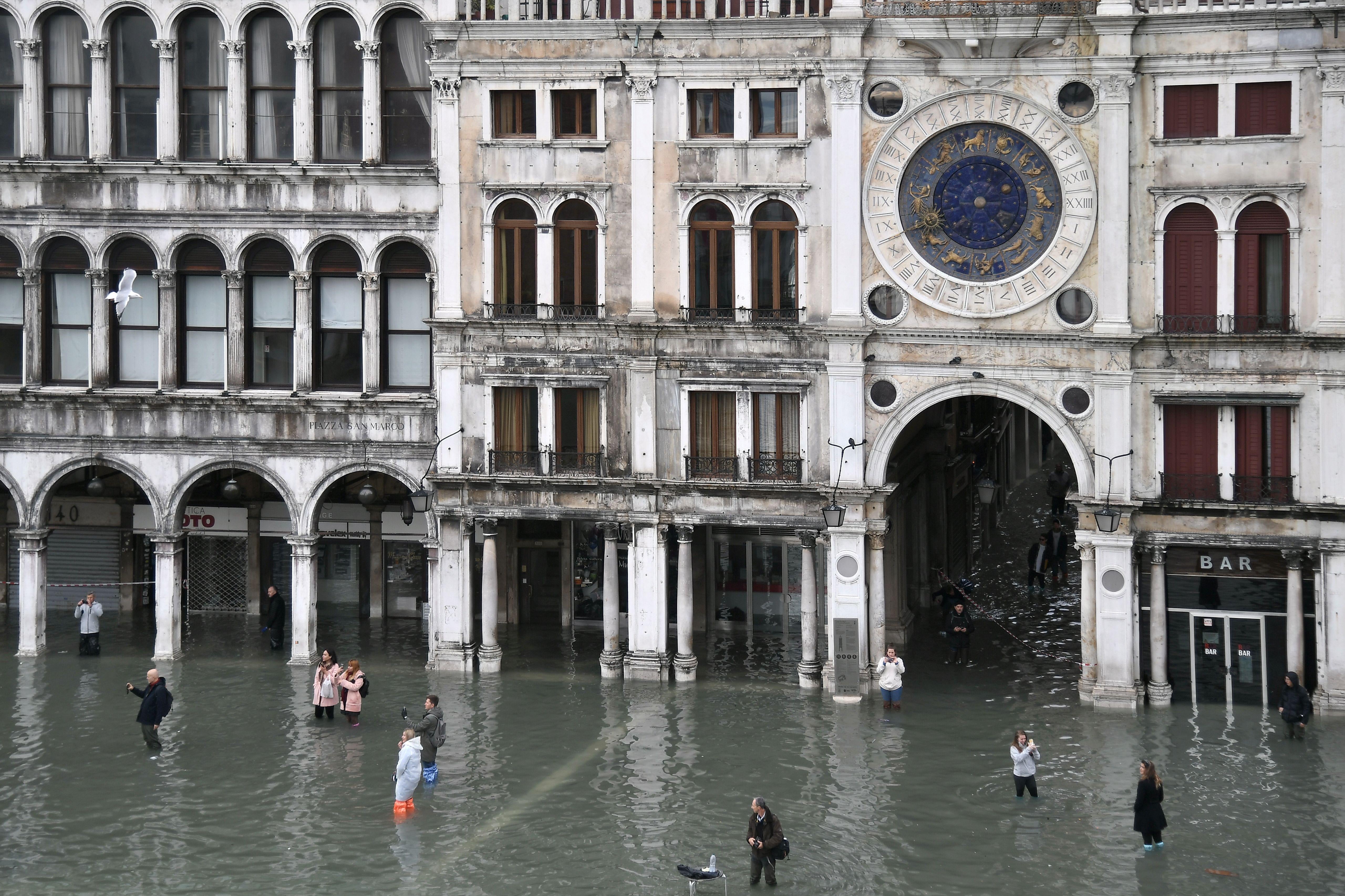 People walk across the flooded St. Mark’s Square.