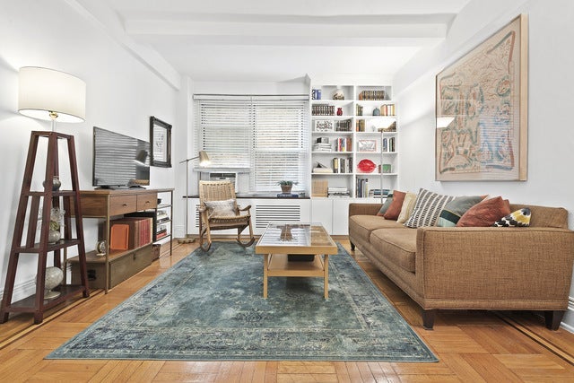 A tastefully decorated living room with a couch, a coffee table, bookshelves, and hardwood floors