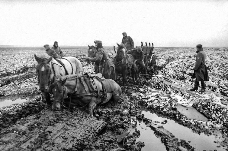 A team of horses mired in mud, with soldiers trying to get them out 