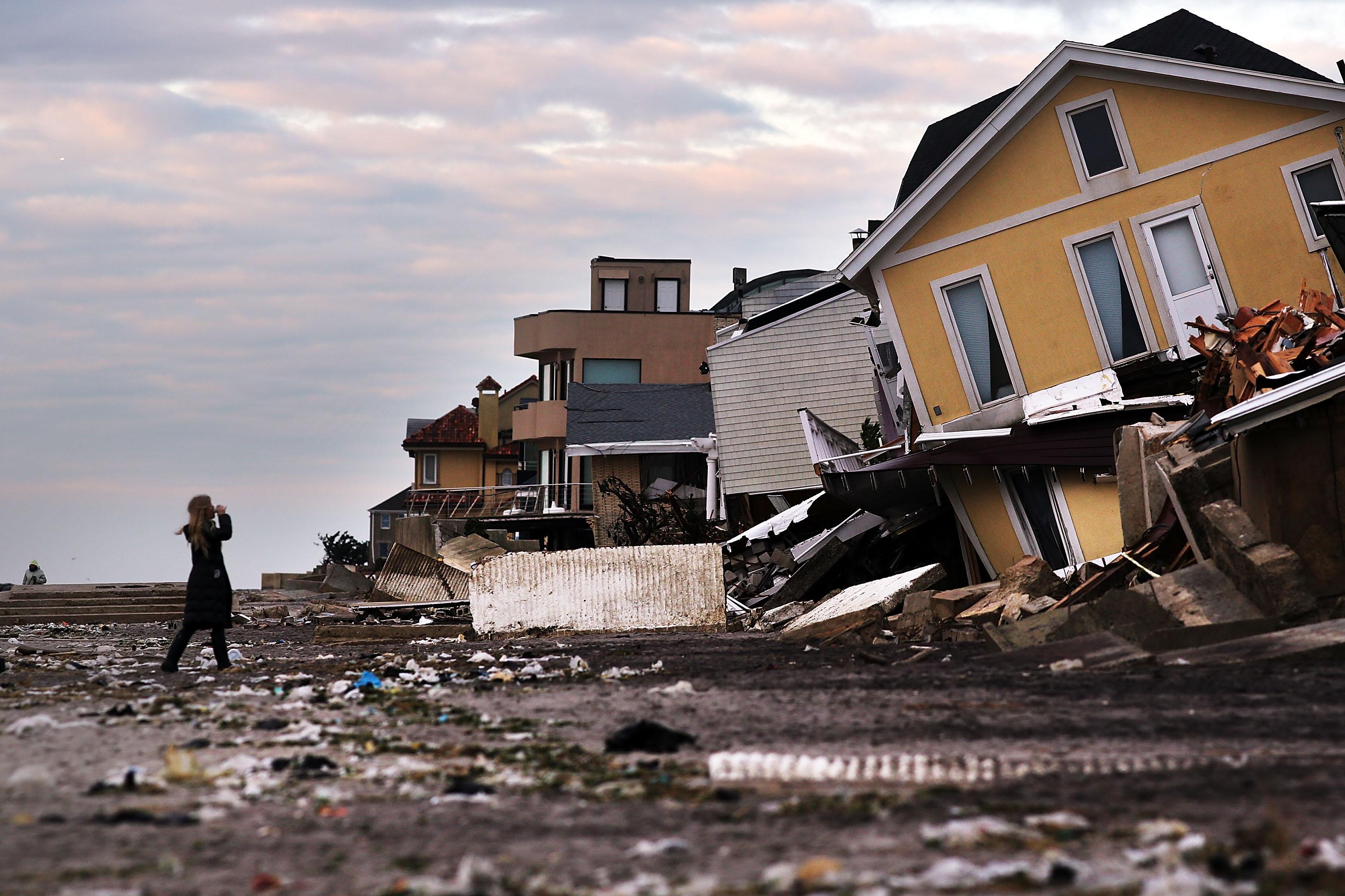 A woman walks along the beach in the heavily damaged Rockaway neighborhood, in Queens where a large section of the iconic boardwalk was washed away on November 2, 2012 in New York.