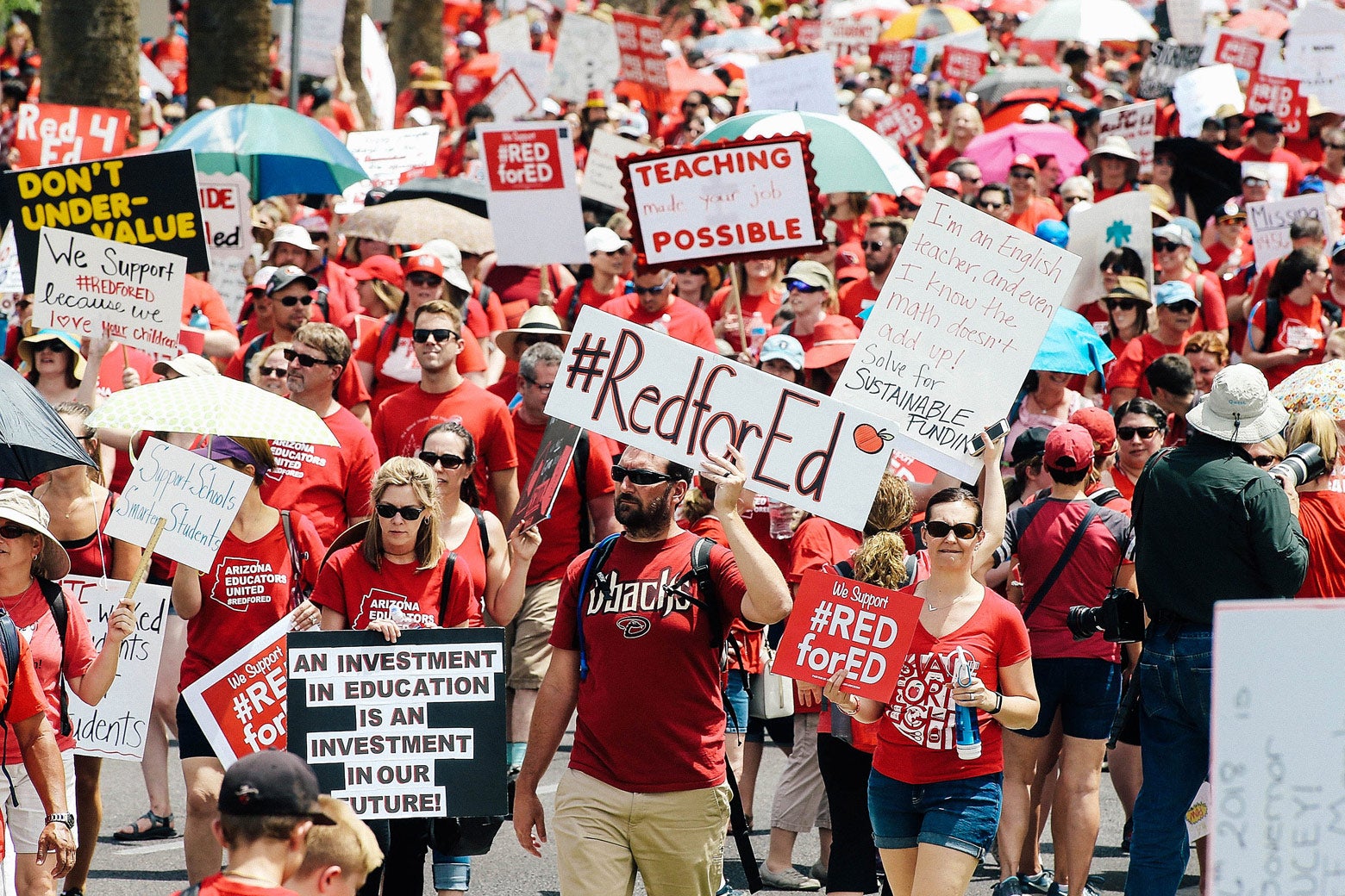 Teachers dressed in red march toward the capitol with signs.