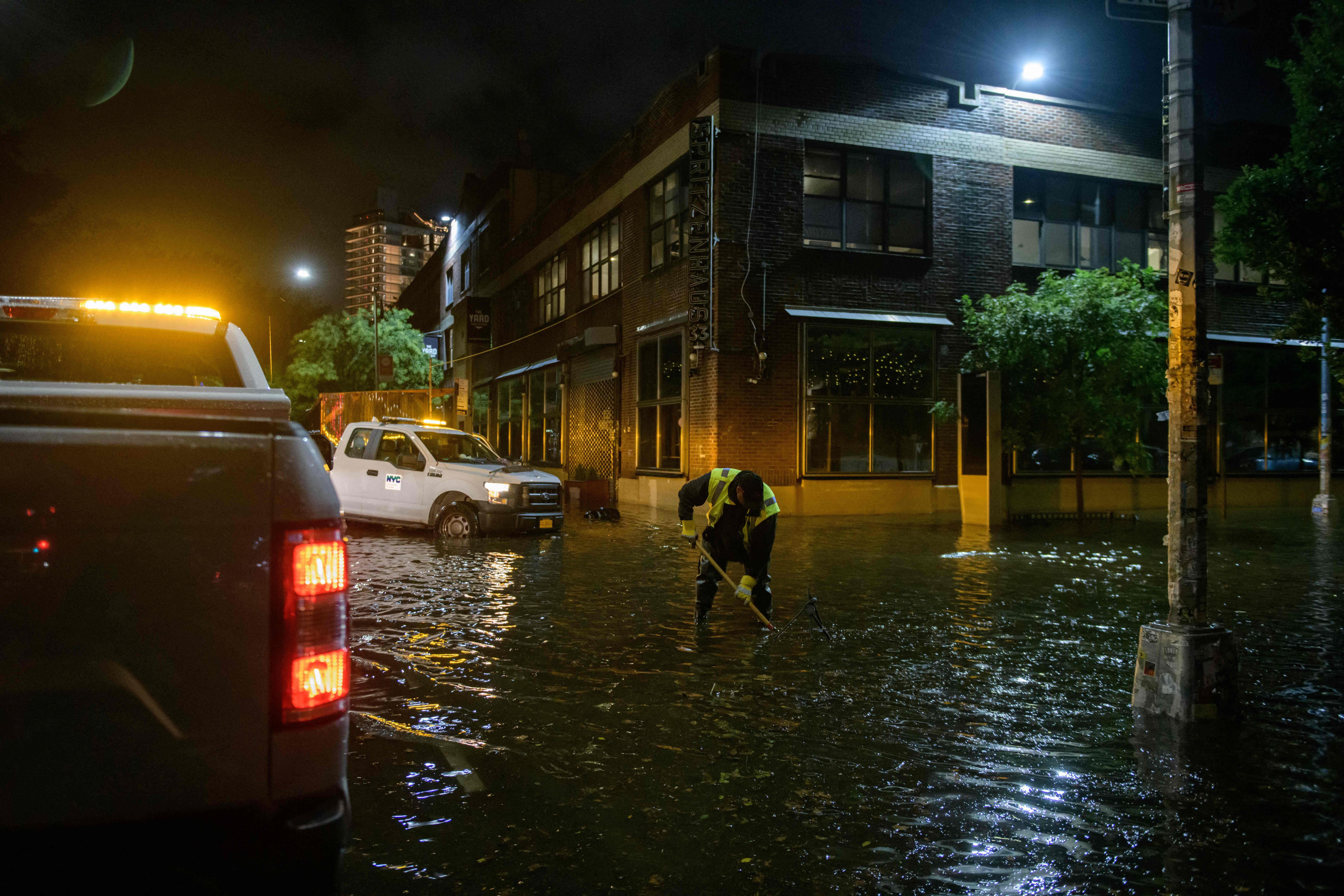 A worker unblocks drains on a street affected by floodwater in Brooklyn.