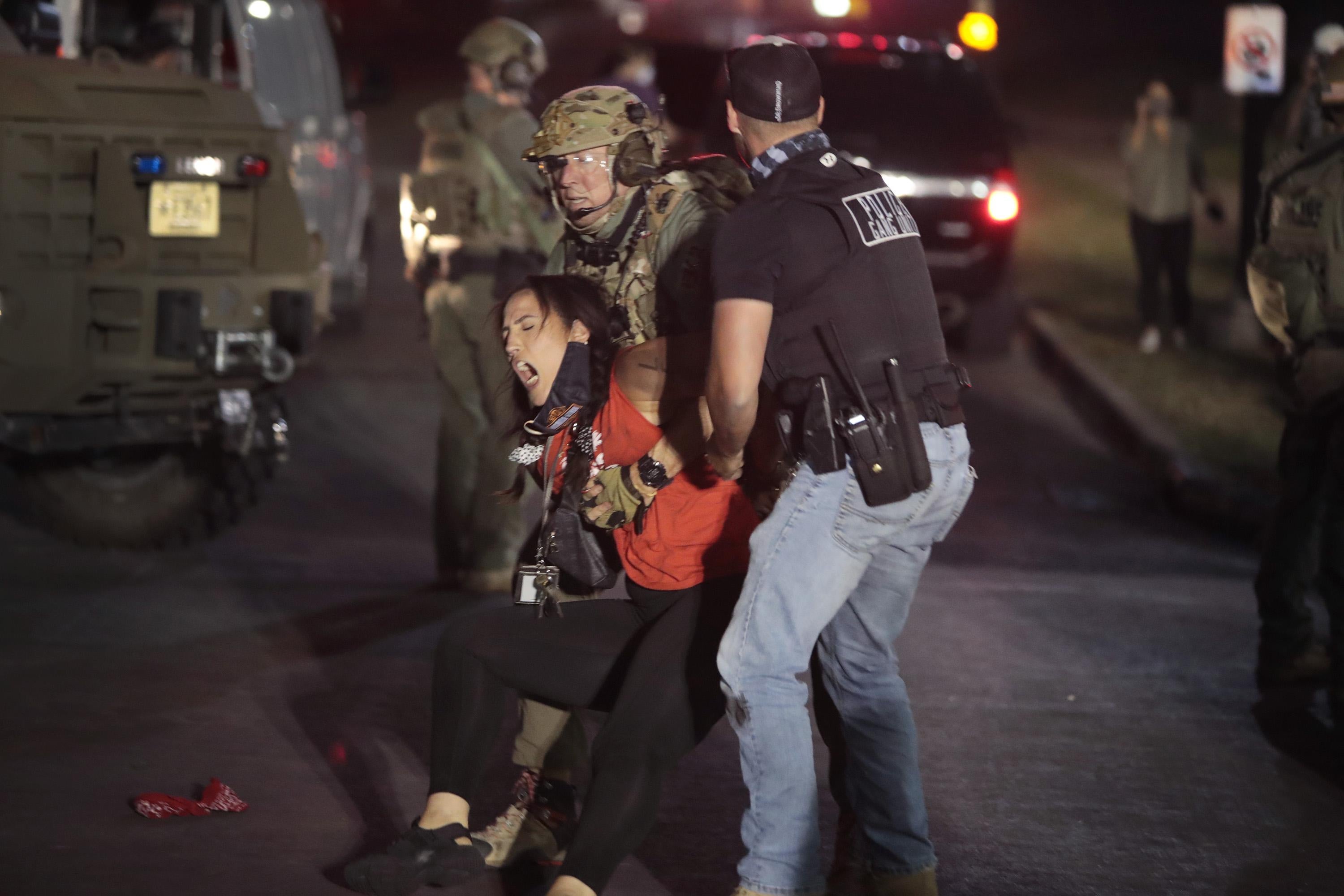 A National Guardsman and a plainclothes law enforcement officer grab a screaming woman