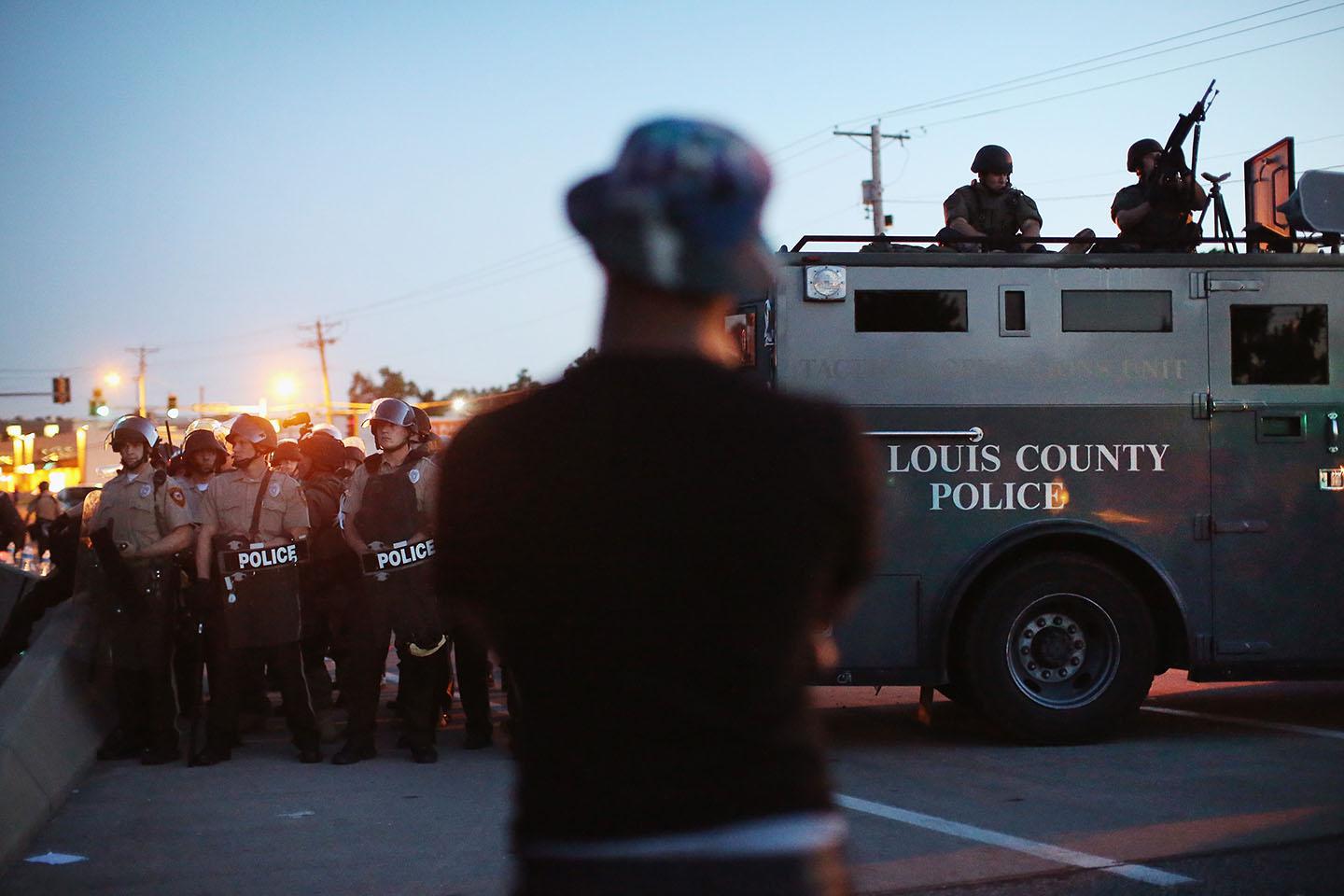 Police stand watch as demonstrators protest the shooting death of teenager Michael Brown on August 13, 2014 in Ferguson, Missouri. 