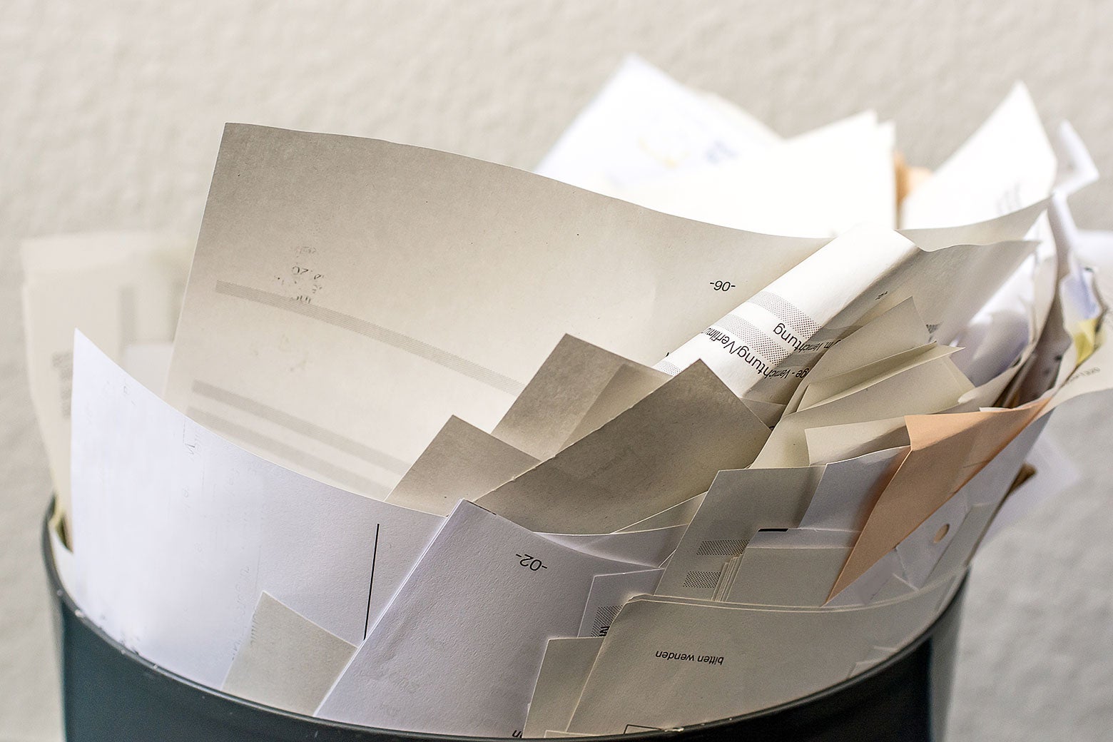 A wastebasket filled with miscellaneous papers.