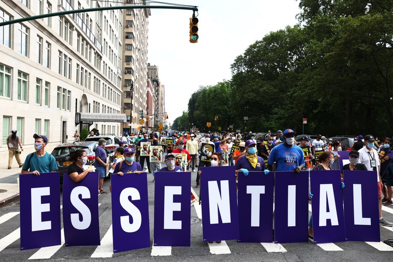 Members of the 32BJ union hold up signs spelling out "Essential Workers" during a "Strike for Black Lives" rally.