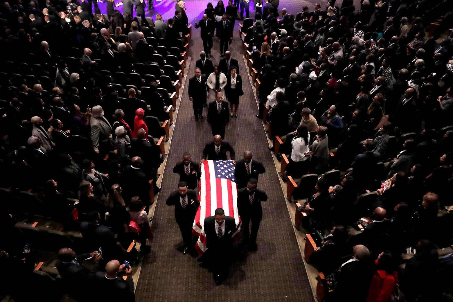 Pallbearers carry a casket with an American flag on it.