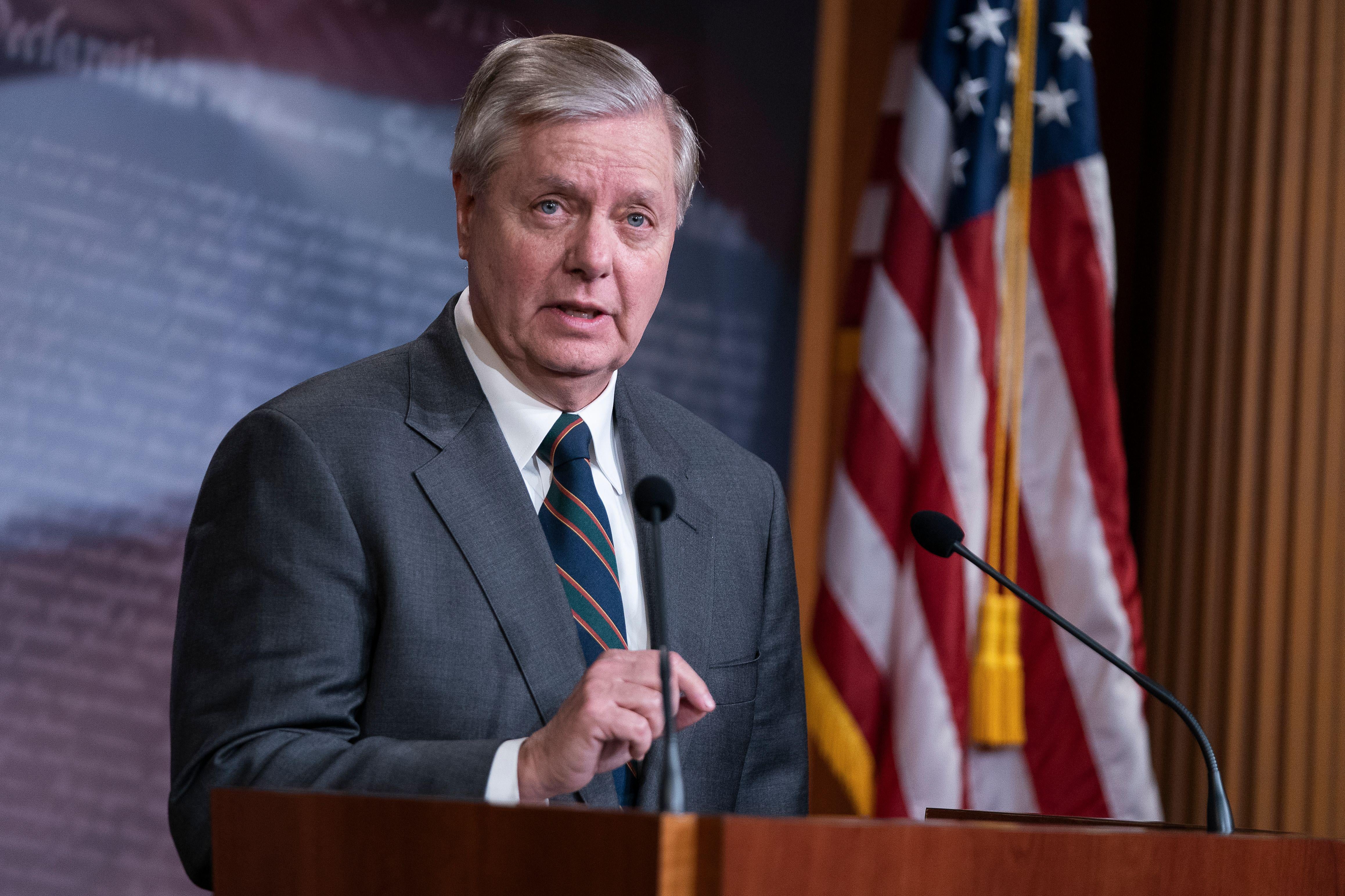 Lindsey Graham speaks at a podium with an American flag in the background
