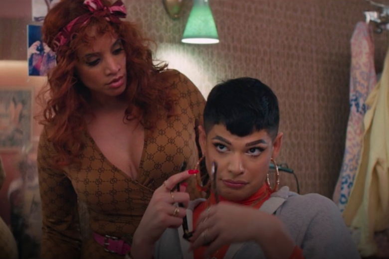 Dascha Polanco stands over Valentina, who looks up while holding a pair of sunglasses.