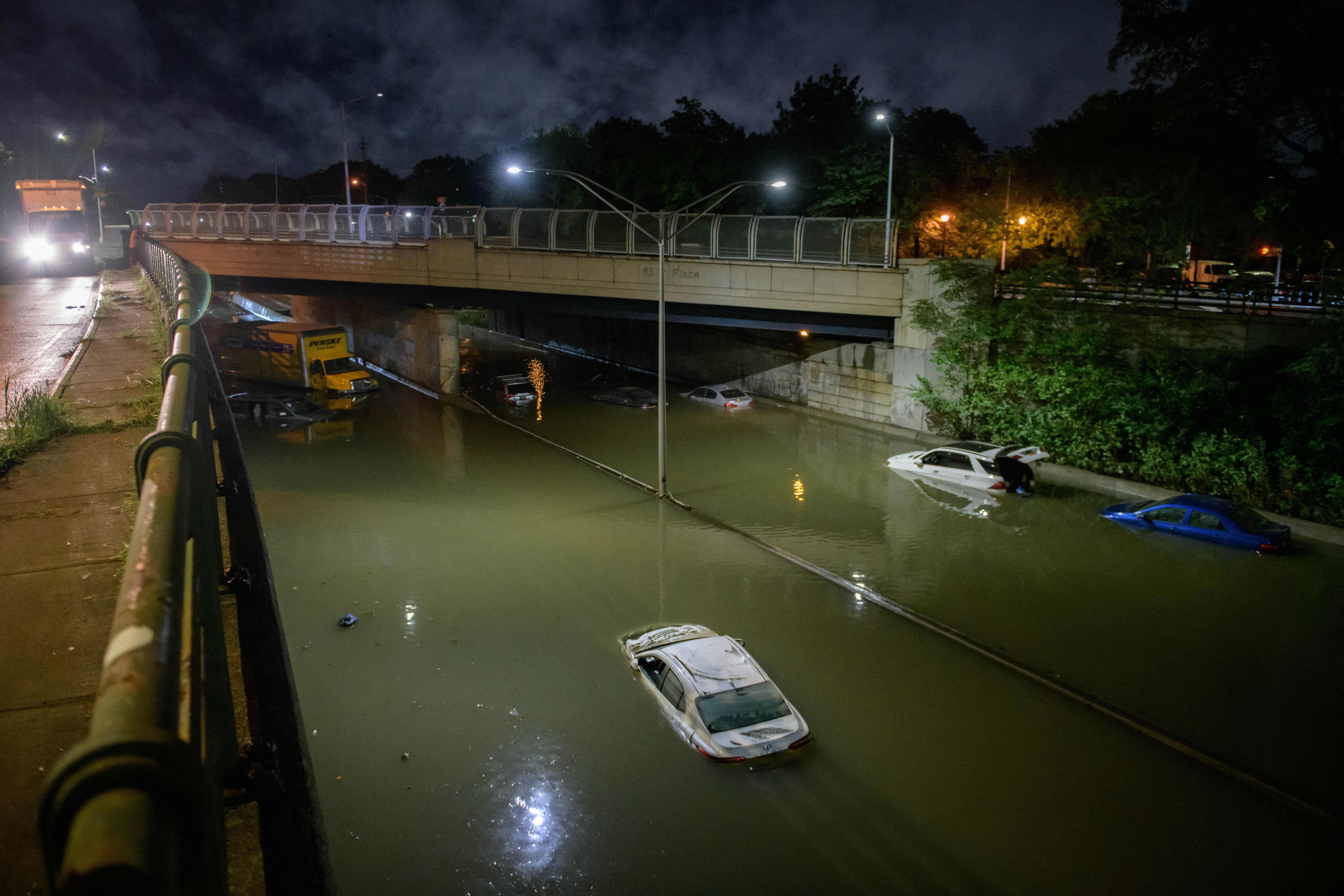 Floodwater surrounds vehicles following heavy rain on an expressway in Brooklyn.