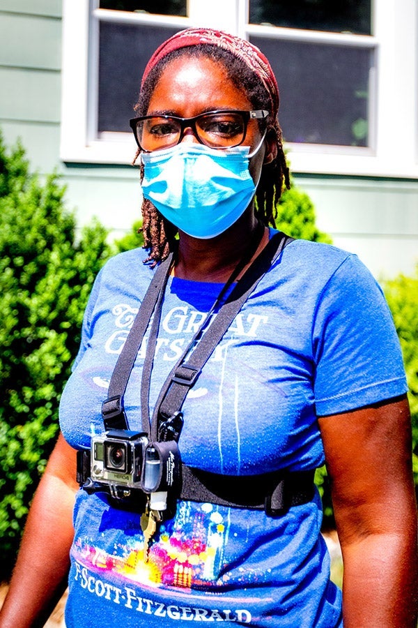 A woman in a face mask and a Great Gatsby T-shirt wears a GoPro strapped to her chest.